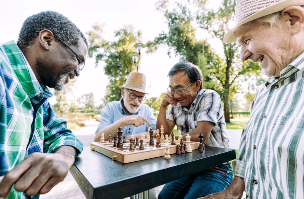 A group of senior friends work on their chess strategies together in a public park on a beautiful, sunny day
