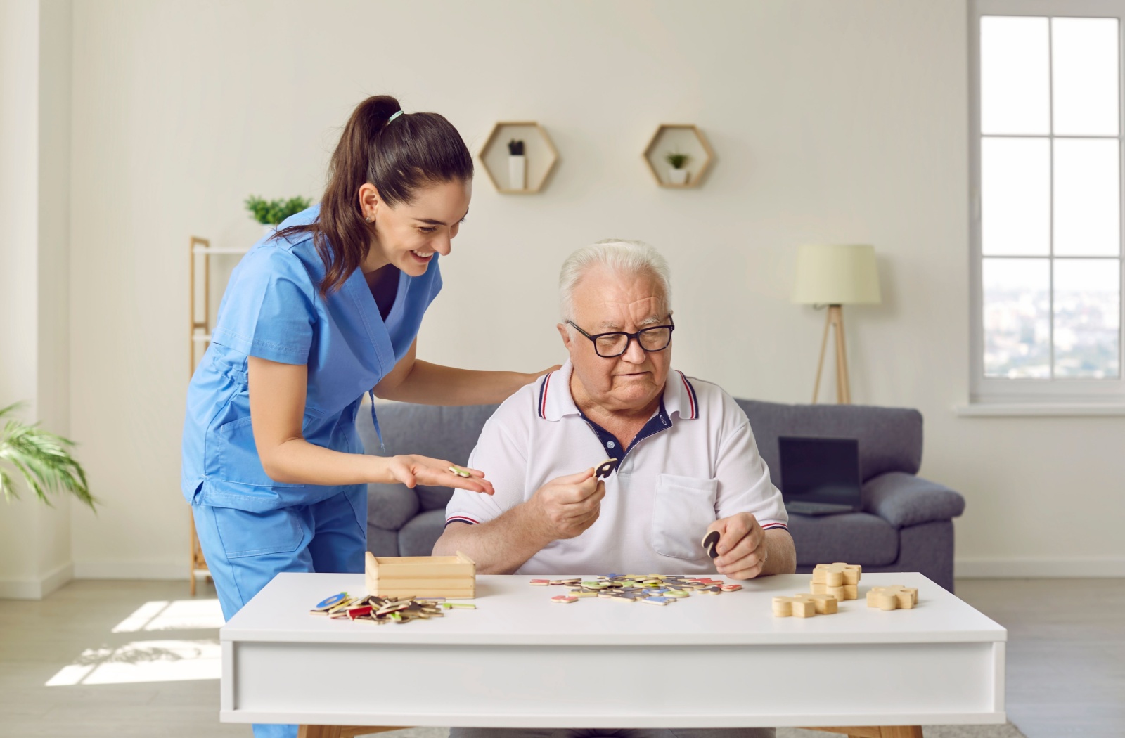 A caregiver assists a senior memory care resident with a cognitive puzzle.