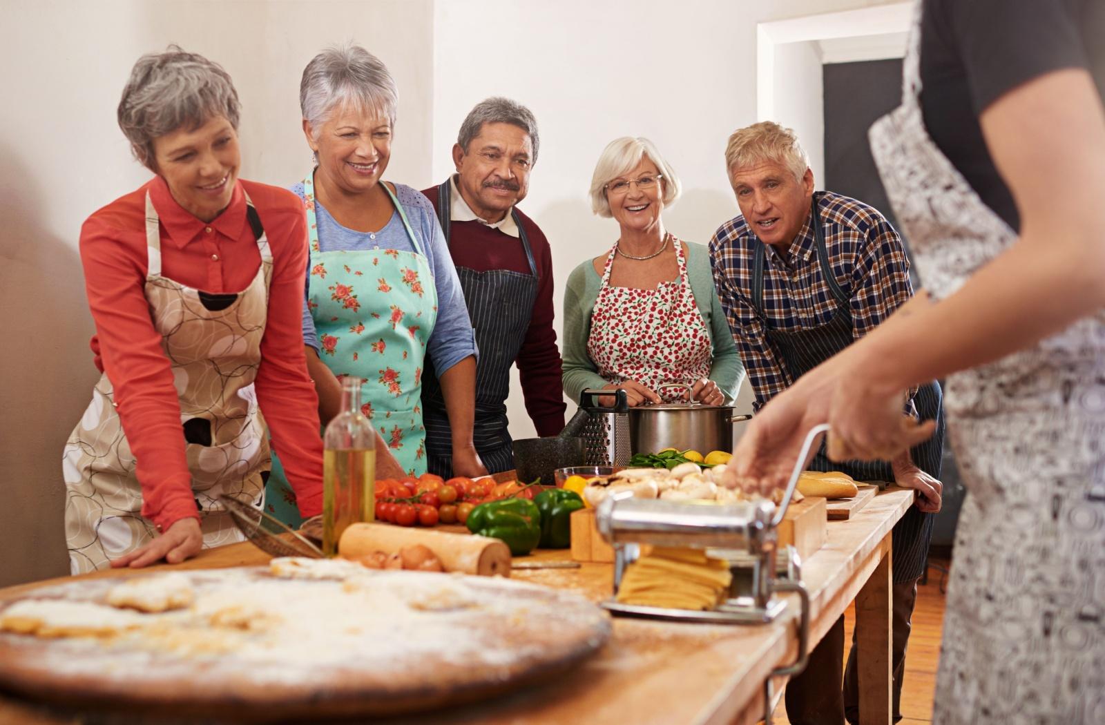 A group of senior friends smile as they take a cooking class together.